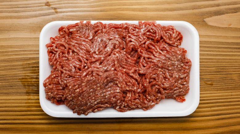 Tray of raw ground beef on wooden table