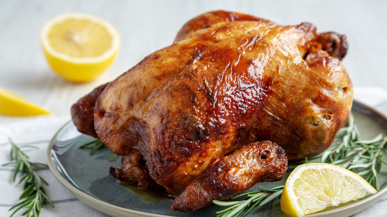 Rotisserie chicken on plate with lemon and herbs