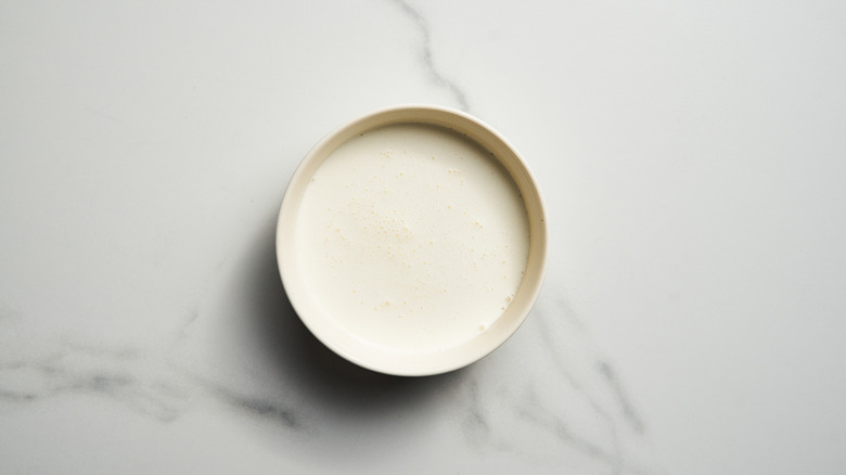 Heavy cream in white bowl on marble background