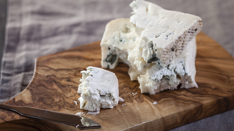 Crumbled blue cheese on wooden board