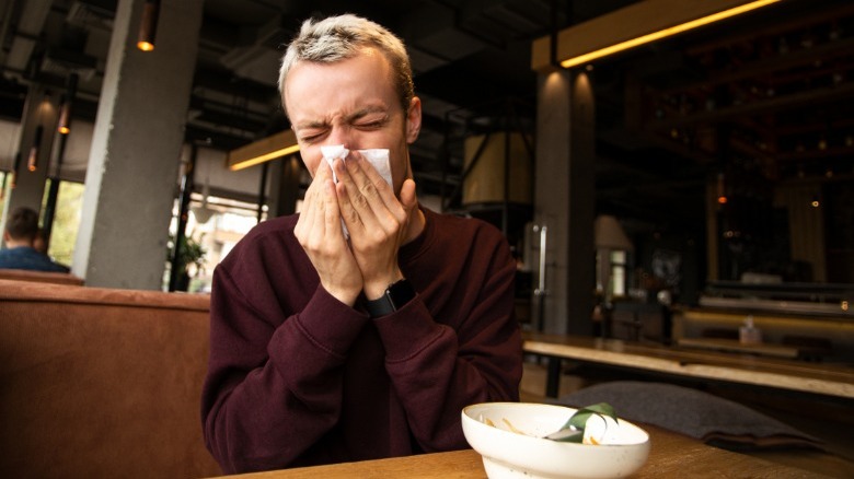 man blows nose in resturant