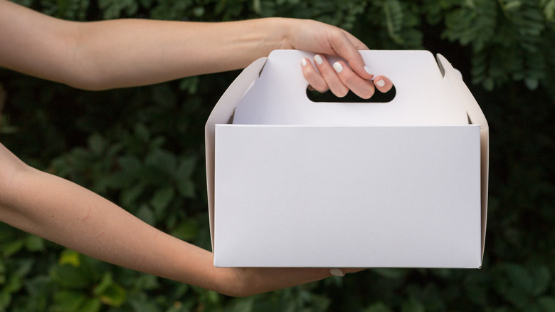 person holding white cake box