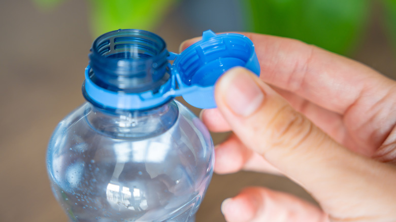 Bottle of drinking water, with a hand removing the cap