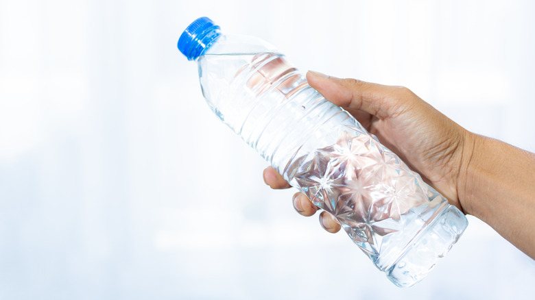 Hand holding plastic bottle of water