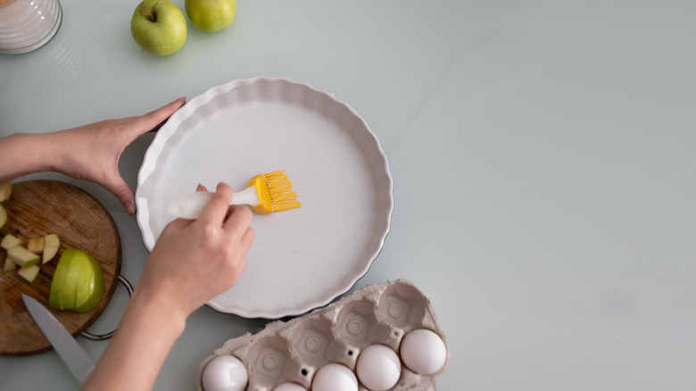 person greasing pie dish