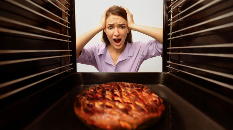 Woman looking at burnt pie in the oven