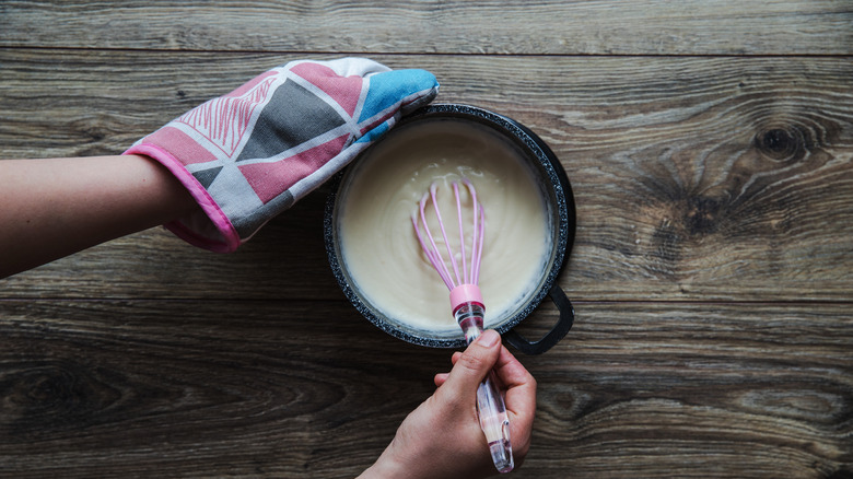 person whisking white sauce