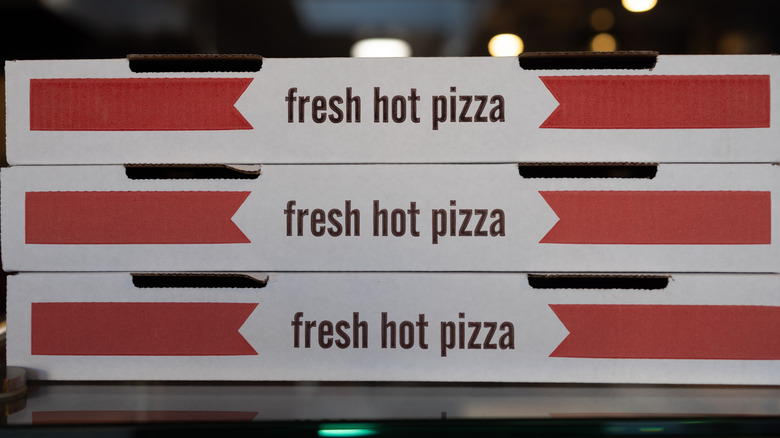 Stacked pizza boxes, with "fresh hot pizza" written on the side of each one