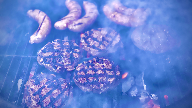 blue smoke over sausages and burgers