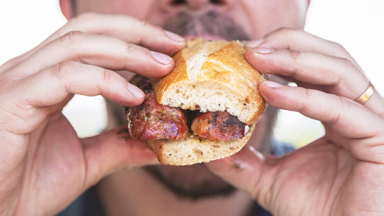 man eating sausage sandwich