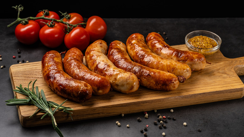 cooked sausages on wooden board