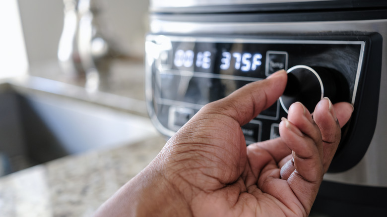 person setting air fryer temperature