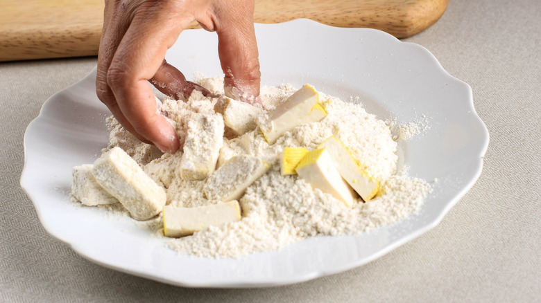 person coating tofu