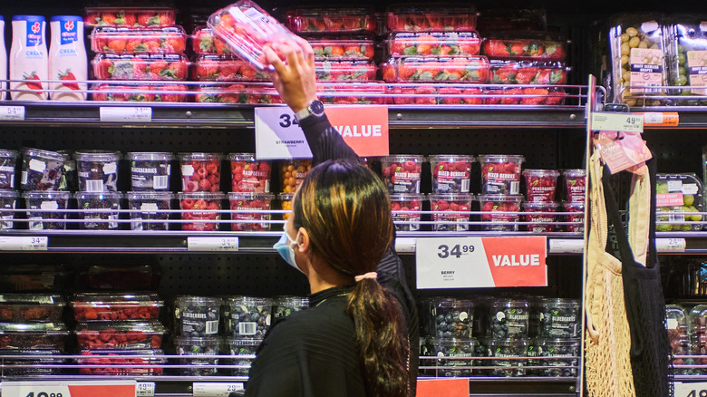 Person choosing strawberries at store