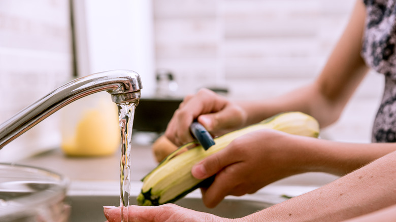 peeling zucchini over sink