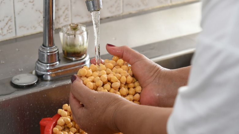 person rinsing chickpeas under tap