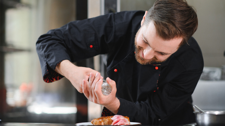 Chef grinding pepper onto steak