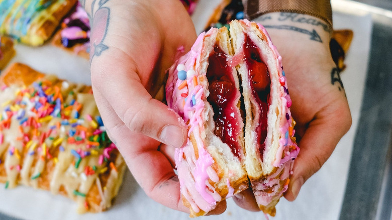 Person holding filled pink pastry