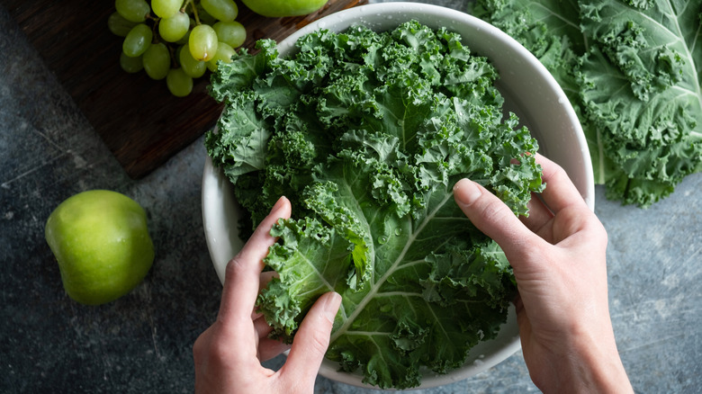 person washing kale in bowl