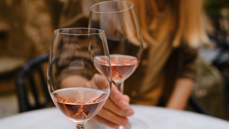 Person holding glass of rosé wine