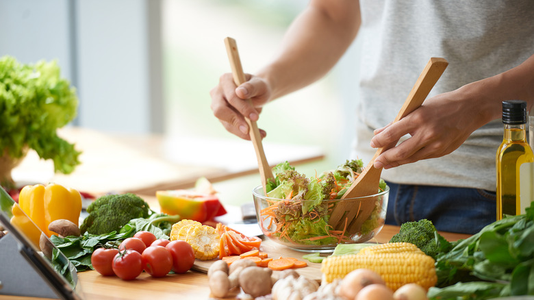 person tossing salad in bowl 