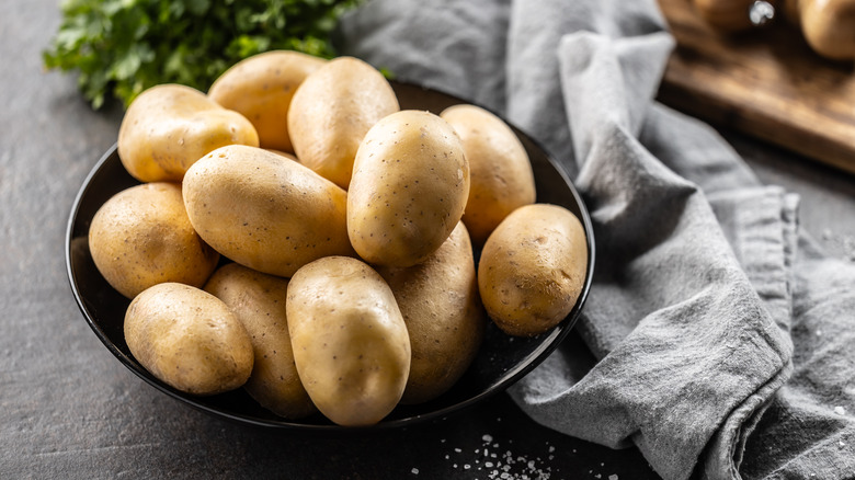 A black bowl of yellow raw potatoes