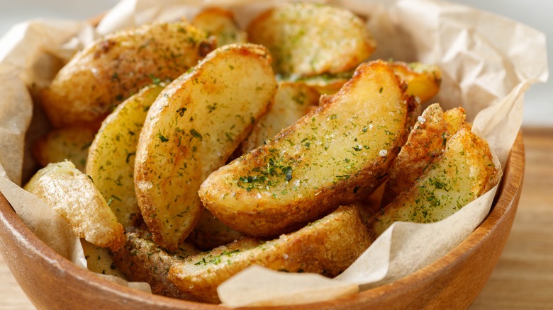 Seasoned potato wedges in a bowl with paper