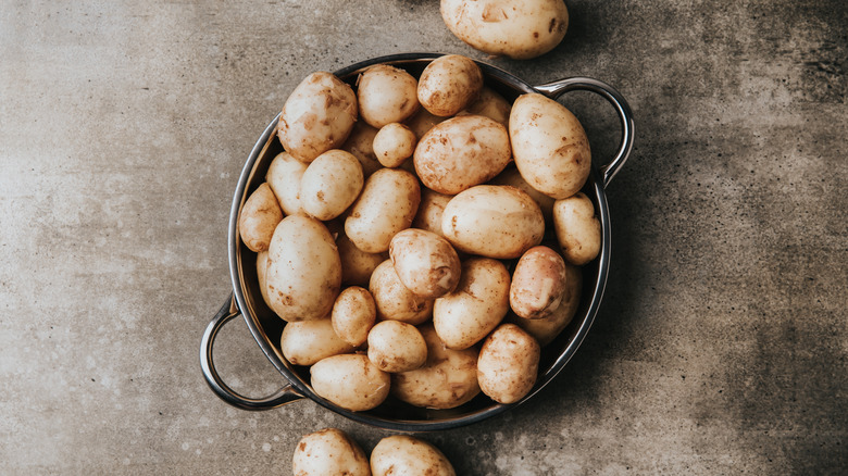 Some raw potatoes in a metal pot