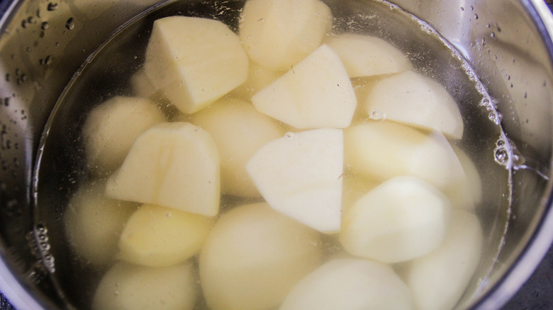 Potato chunks that are submerged in a pot of water