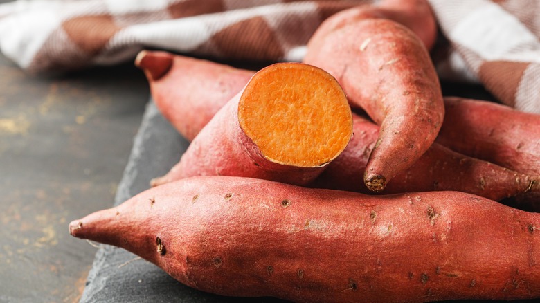 A pile of cut and whole sweet potatoes