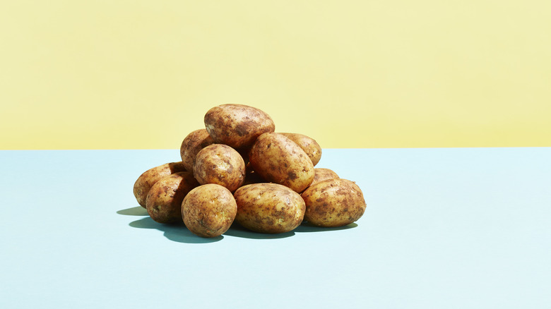 A pile of tan potatoes shown with a colorful backdrop