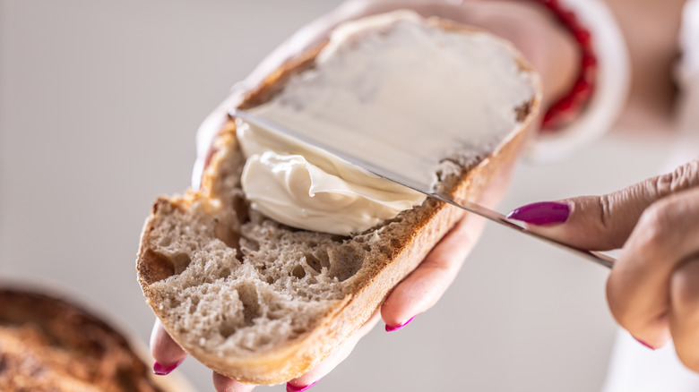 person spreading margarine onto bread