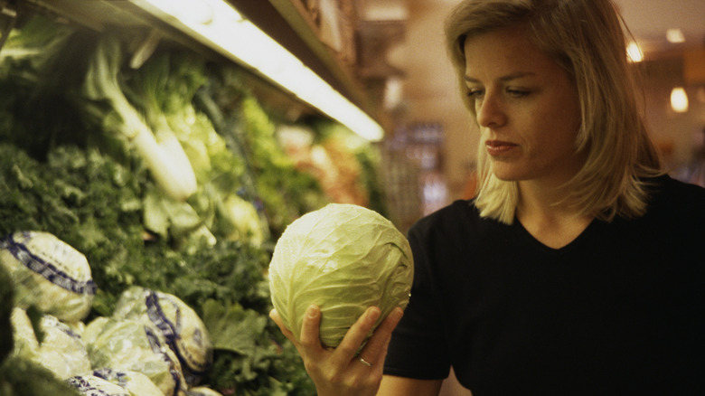 Woman examining a cabbage in store