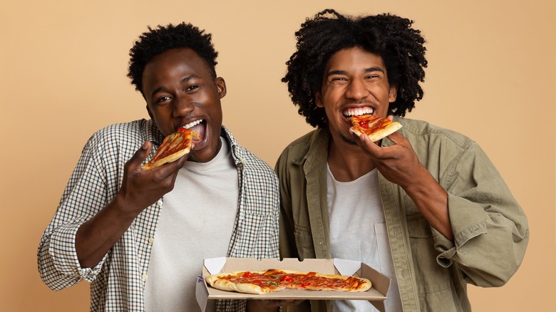 Two guys eating pizza