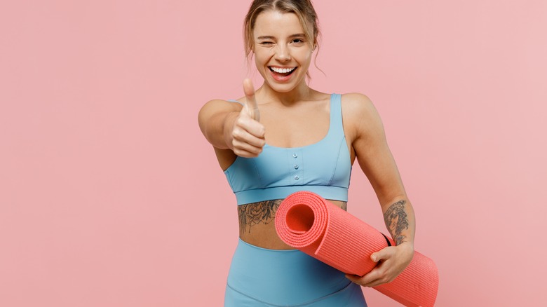 woman smiling holding yoga mat