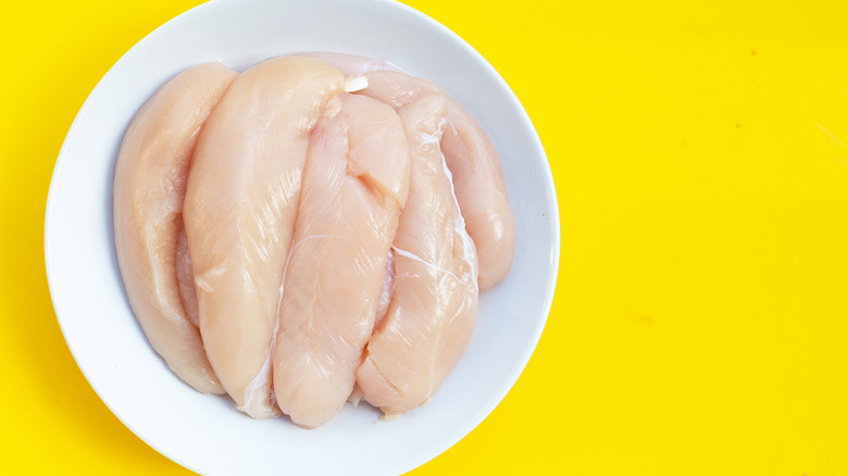 Raw chicken tenders on yellow background