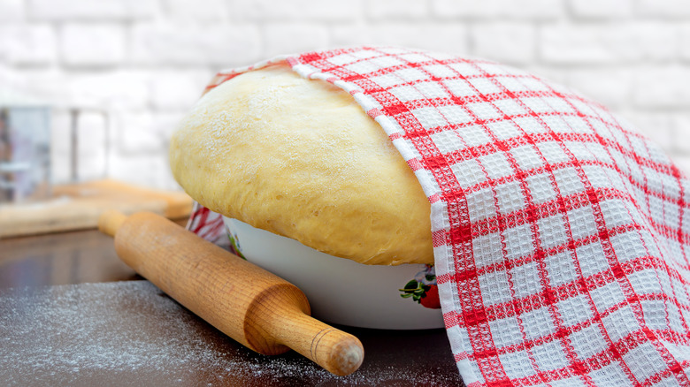 dough covered by tea towel rolling pin