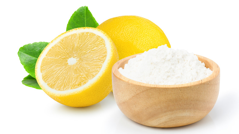 wooden cup of baking soda and a lemon white background