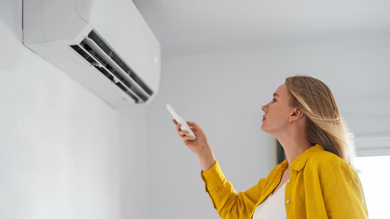 woman turning on air conditioning white room