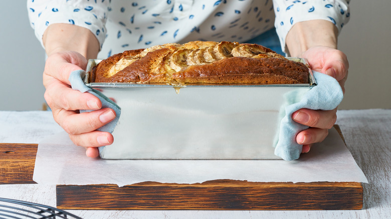 Hands holding bread in a loaf pan