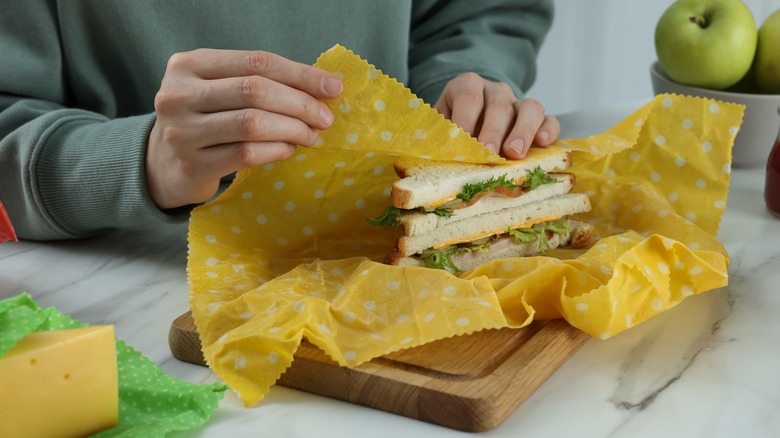 person wrapping sandwich in paper