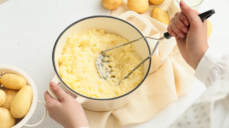 person mashing potatoes