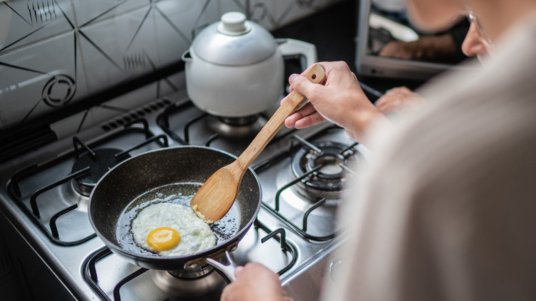 person frying egg in skillet