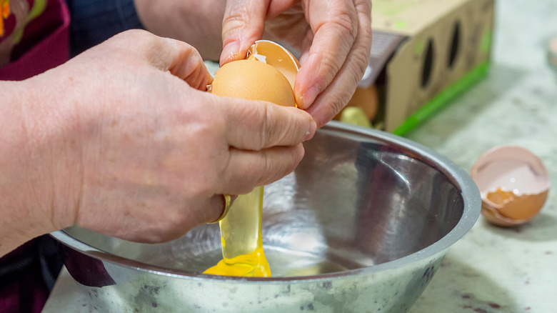 hands cracking egg over bowl