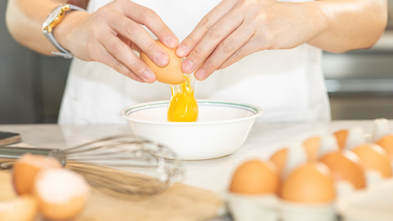 person cracking egg into bowl