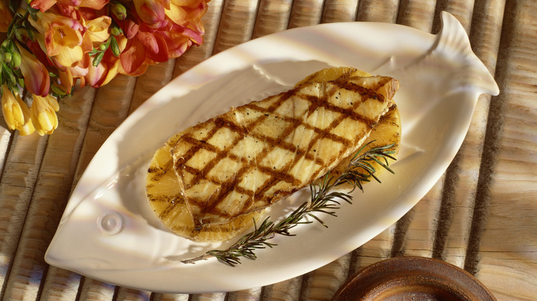 Grilled fish steak sitting on top of grilled pineapple slices