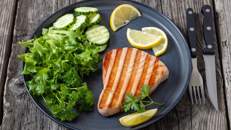 Grilled tuna steak with salad leaves and lemon slices