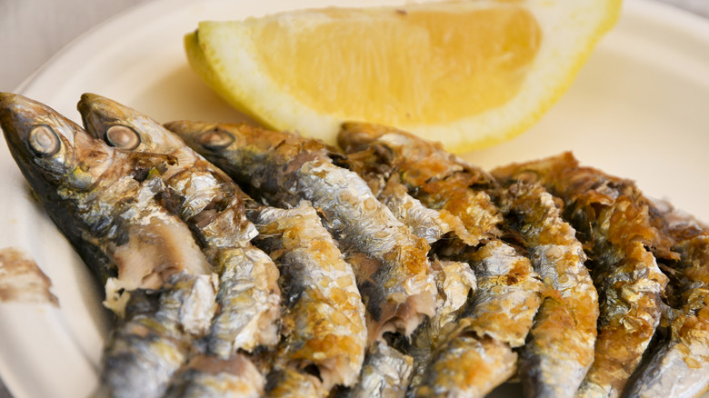 Grilled sardines on plate with wedge of lemon