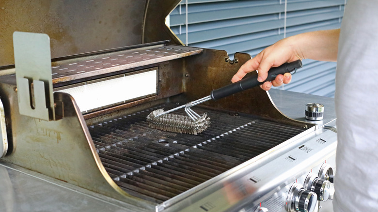 person cleaning grill with wire brush