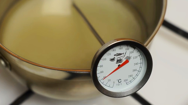 Thermometer measuring cream in saucepan